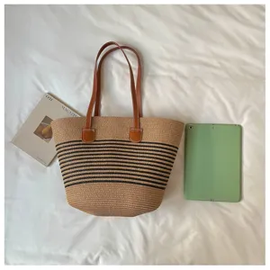 Large straw woven beach tote bag shown next to a tablet for size comparison scale.