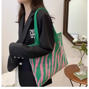 Vibrant green and pink zebra pattern knit tote bag shown on a stylish fashion model.