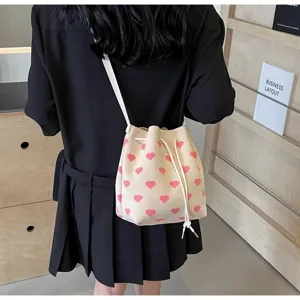 Rear view of knit bucket bag with pink heart pattern worn with black pleated skirt