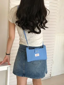 Detailed shot of casual blue quilted mini cross-body phone bag worn by model, summer style.