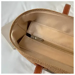 Detail view of the interior fabric lining and zipper closure of the straw beach tote bag.