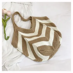 Boho style woven shoulder bag with brown and white chevron pattern displayed on white fabric