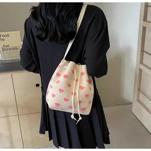 Close-up of heart pattern fabric on a beige drawstring bucket bag worn by model