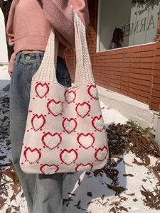 Borsa tote in maglia con motivo a cuore rosso tenuta da una persona nella neve