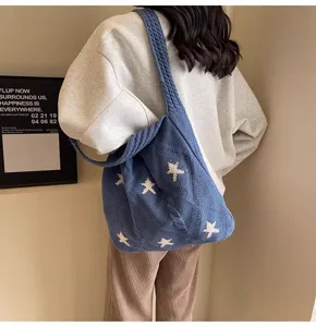 Close-up detail of blue knitted tote bag with white star patterns worn by a model