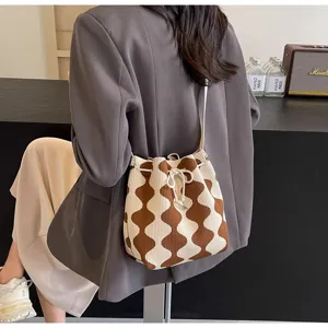 Detailed view of a brown and cream diamond-patterned knitted drawstring bucket bag.