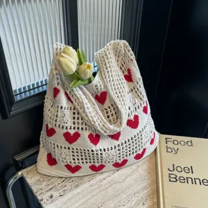 Close-up of white knitted tote bag with red heart pattern and hollow design