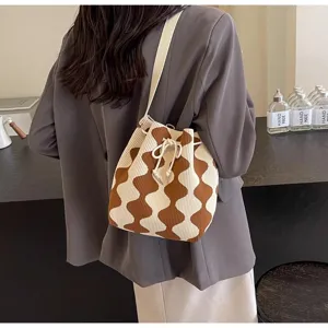 Close-up of a wavy pattern knit bucket bag with a cream drawstring and brown waves