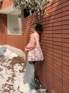 Elegante borsa tote in maglia con motivi a cuore rosso in un ambiente lifestyle all'aperto