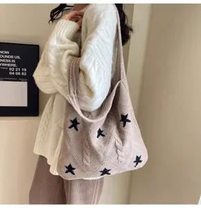 Detailed view of a beige cable knit tote bag with black stars carried by a model