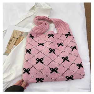 Detail shot of a pink knitted tote bag featuring black bow patterns and diamond grid