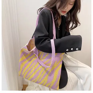 Detailed view of a purple and yellow zebra pattern knit shoulder bag worn by a model