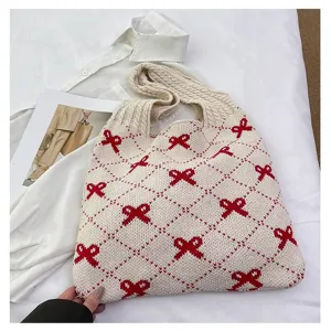 Close-up detailed view of the red bow jacquard pattern on the cream knitted tote bag