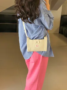 Detailed shot of a stylish white quilted crossbody mini bag worn by a model in casual outfit.