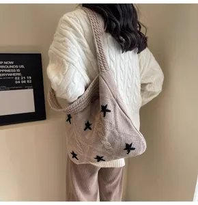 Detailed shot of beige knitted tote bag with black star pattern on model's shoulder