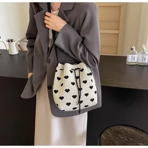Lifestyle view of a model wearing a knitted bucket bag with black heart patterns