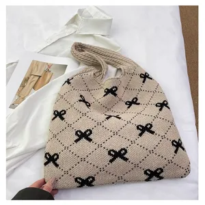 Detailed macro view of beige knitted tote bag with black bow and diamond patterns