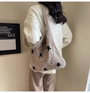 Lifestyle detail of a woman carrying a beige knitted star pattern shoulder bag