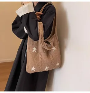 Close-up of brown knitted tote bag with white star pattern and cable knit texture