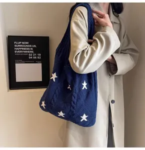 Macro view of navy blue cable knit tote bag with contrasting white star patterns
