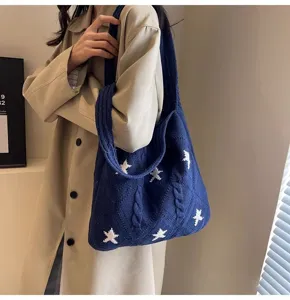 Detailed macro view of a navy blue knitted tote bag with white star patterns on model