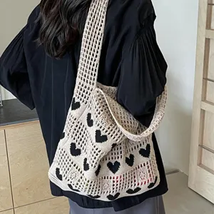 Detail shot showing the black heart pattern on a cream hollow-out knit tote bag