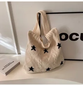 Detailed view of cream knitted tote bag featuring black star patterns and cable textures.