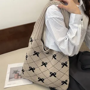 Lifestyle view of a large capacity knitted tote bag with black bow patterns and diamond grid.