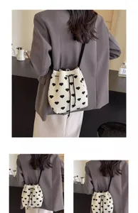 Detail of a white knitted bucket bag with black heart patterns and drawstring closure