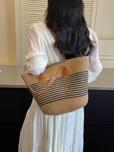 Large straw tote bag with black stripes and brown leather handles for beach trips