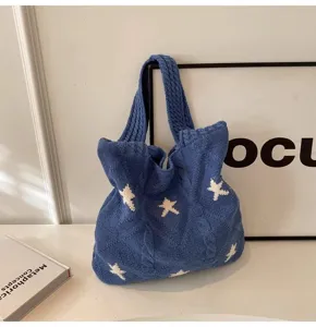 Close-up of a blue knitted tote bag featuring an elegant white star pattern and cable knit texture