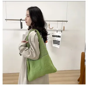 Primer plano de un bolso de malla de punto verde llevado al hombro por una modelo.