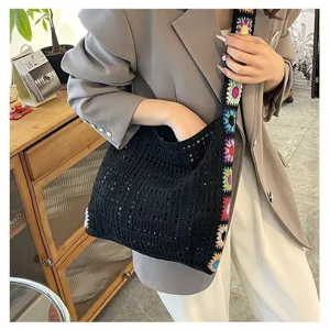 Detail of black crochet tote bag with colorful floral strap in a lifestyle setting