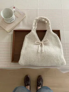 Detailed view of cream white knitted tote bag with decorative bow and soft texture