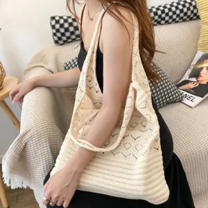 Bolso de mano de punto vintage beige con motivos de corazones, mostrado en un ambiente relajado