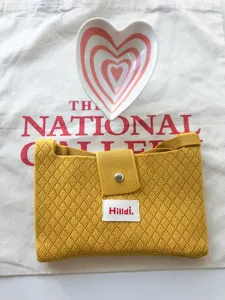 Detailed view of the yellow knitted mini crossbody bag, featuring cute diamond knit and button.