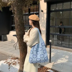 Elegante borsa tote in maglia azzurra con motivo a cuori indossata da una modella