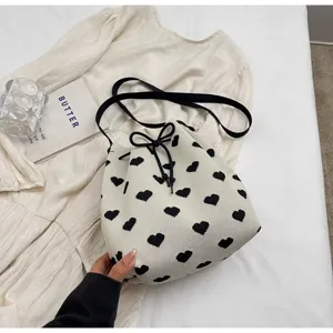Close-up of white knitted bucket bag with black heart patterns and drawstring closure
