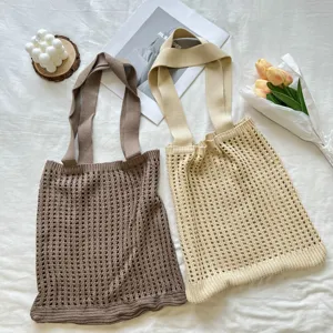 Detail view of brown and beige knitted hollow-out mesh tote bags on white fabric.