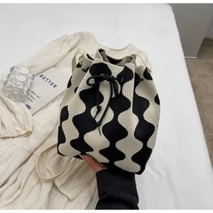 Close-up detail of knit bucket bag featuring black and white wavy pattern and drawstring