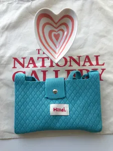 Blue knitted crossbody phone bag with heart dish prop and textured woven design.