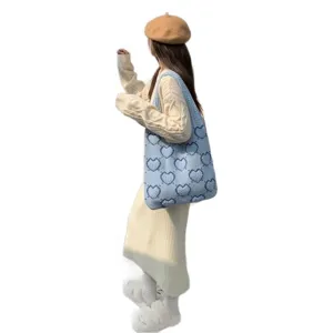 Grande borsa tote in maglia azzurra con motivi a cuore blu mostrata sulla modella.