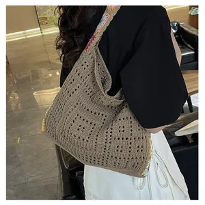 Detailed view of large bohemian knitted tote bag worn by a model in a cafe setting