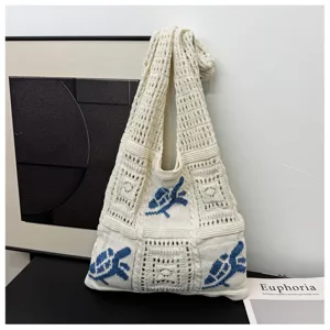 Artistiek detail van een witte gebreide shopper met blauwe schildpadpatronen erop.