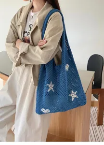 Close-up of blue star-patterned knit tote bag held by model in a casual lifestyle setting