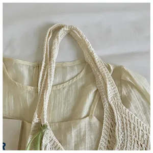 Close-up detail of the hollow-out knit texture on a beige Bohemian beach tote bag.