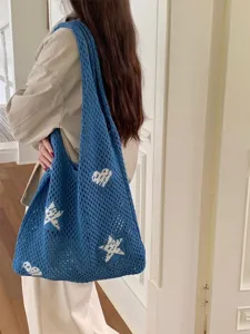 Detailed view of a blue hollow-out crochet tote bag with white star and heart motifs