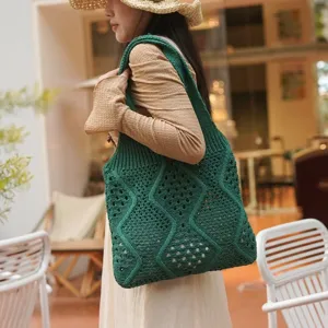 Mujer elegante con un gran bolso tote de ganchillo verde calado en un café soleado