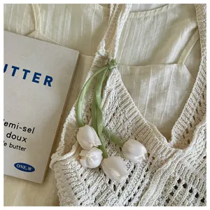 Close-up of bohemian knit beach bag with elegant satin tulip flower charm ornament