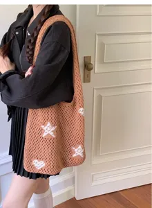 Close-up of a brown hollow-out knit tote bag with white star patterns worn by a model